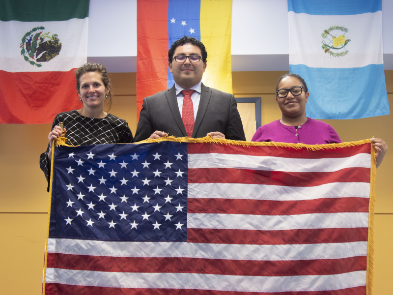 Three EILS staff members holding American flag.